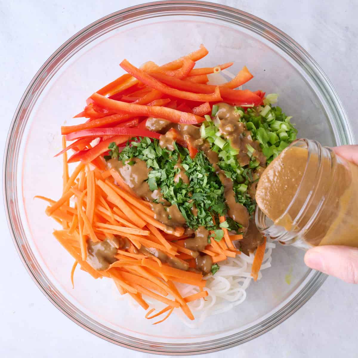 Peanut dressing being poured over salad.