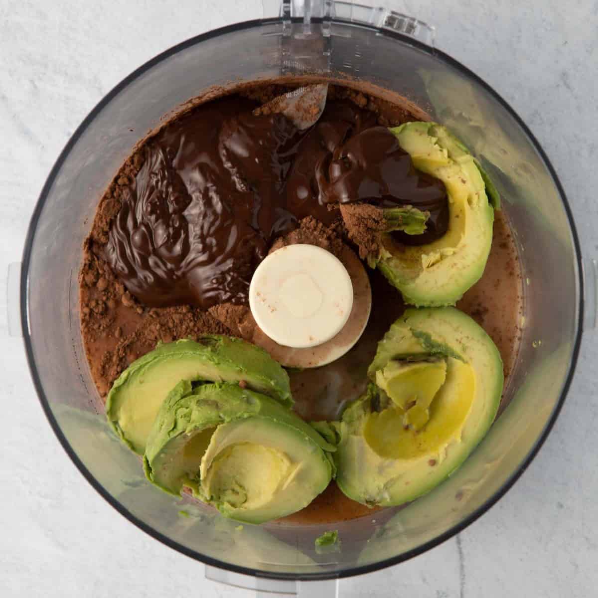 Avocado, chocolate, and cocoa powder in a food processor.