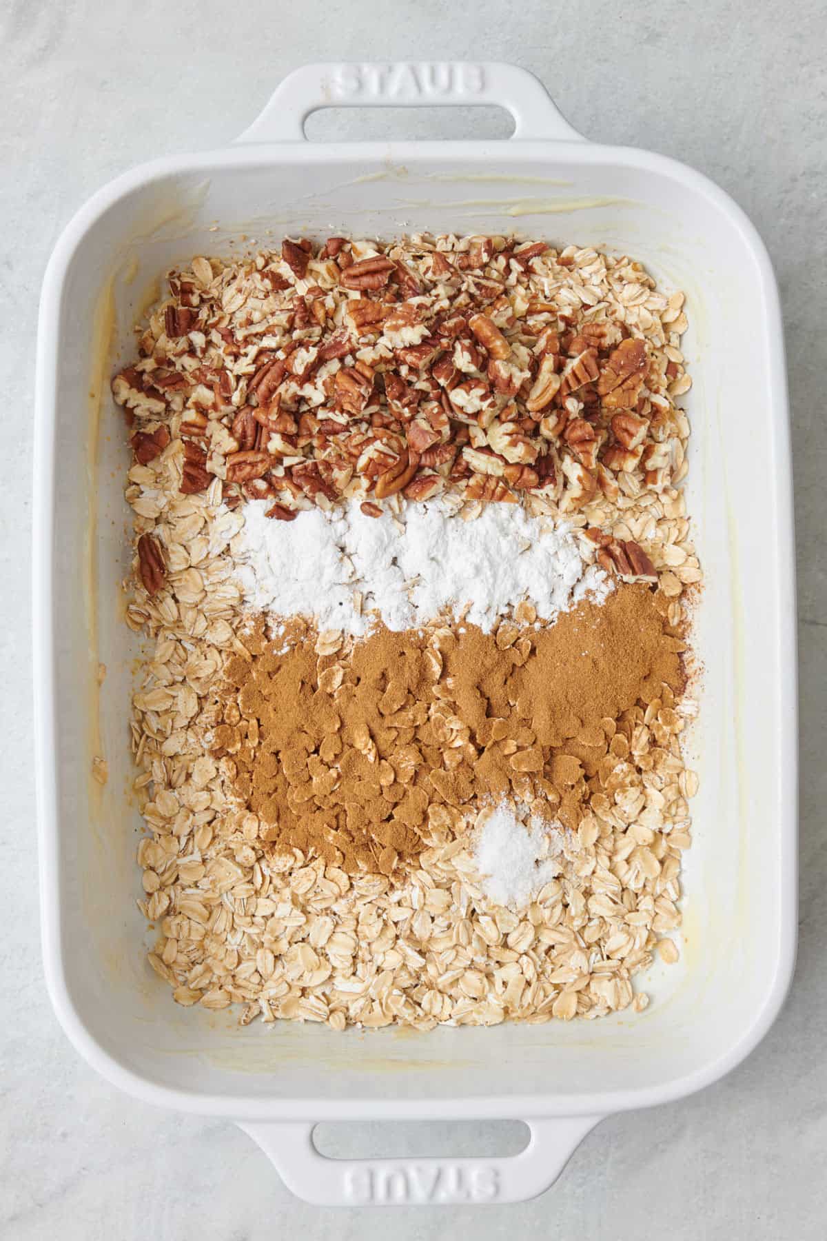 Oats, pecans, cinnamon, baking powder, and salt in a baking dish.