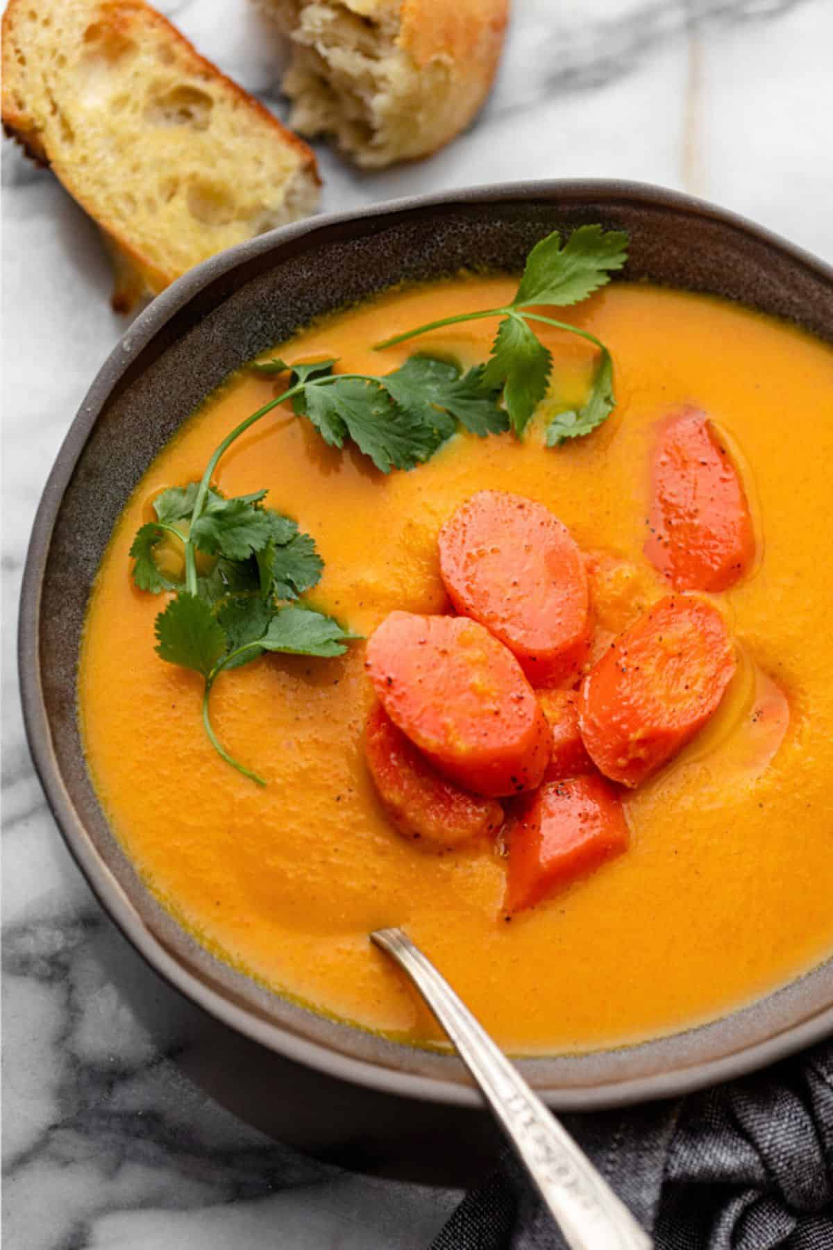 Creamy carrot ginger soup in a bowl with extra roasted carrots on top.