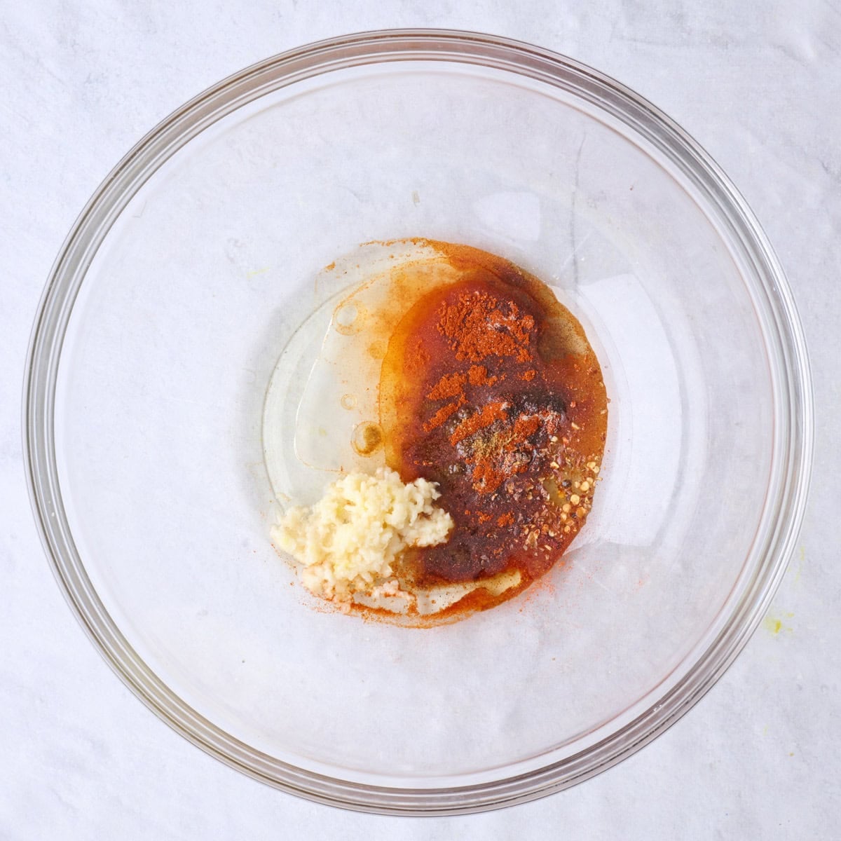 Oil, garlic and spices in a bowl before mixing.
