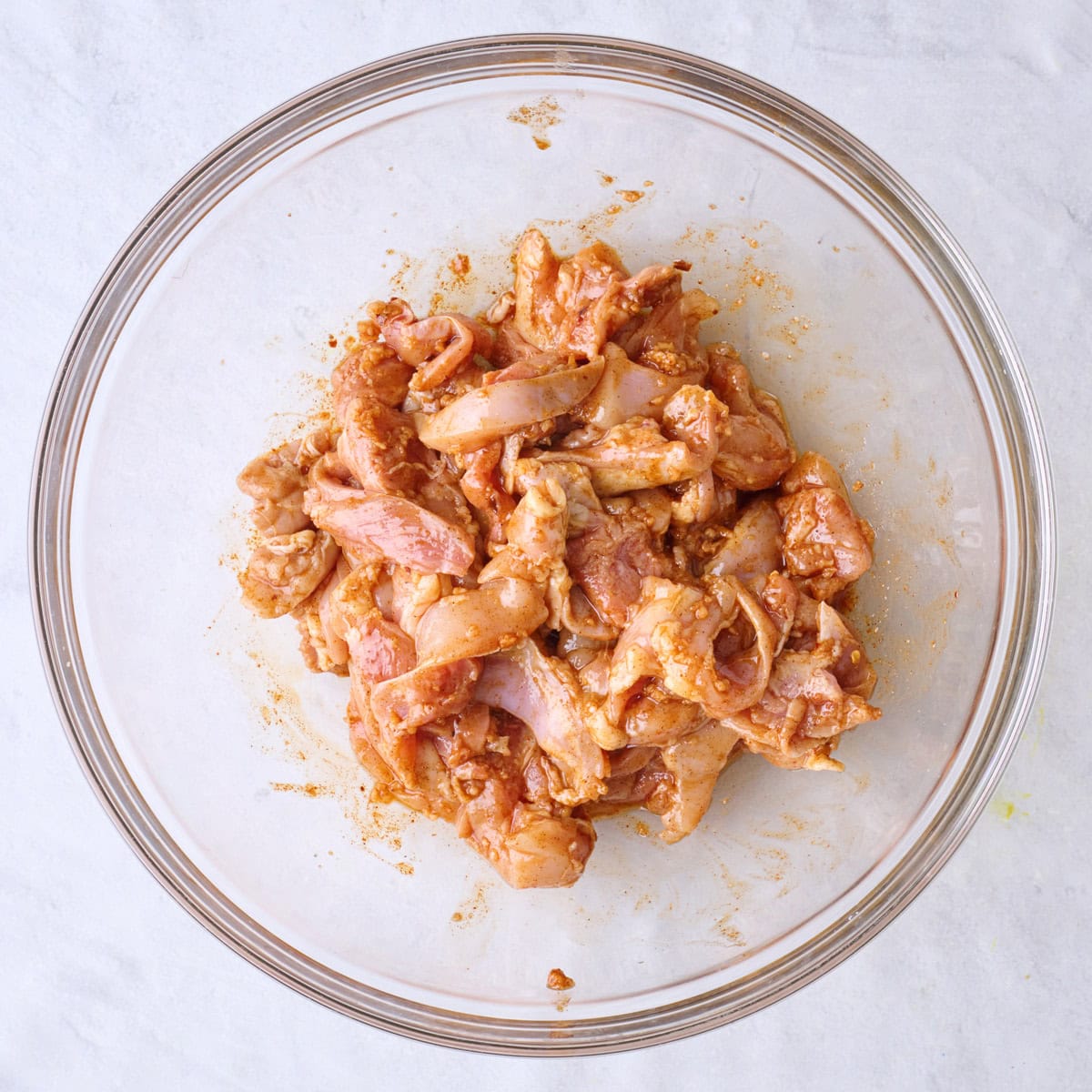 Sliced chicken thighs tossed in marinade.