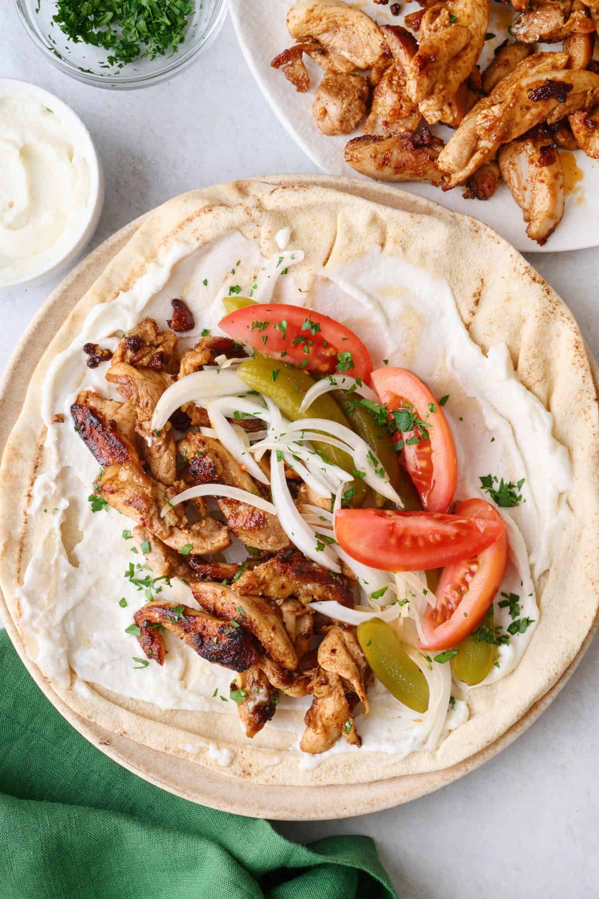 Chicken shawarma on pita with labneh, onions, pickles and tomatoes.