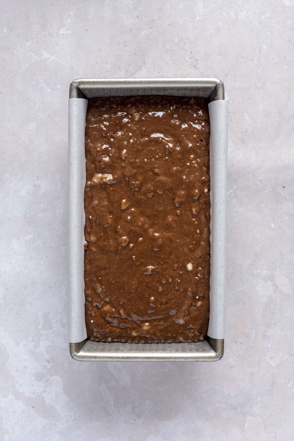 Batter in a parchment lined loaf pan with before baking.