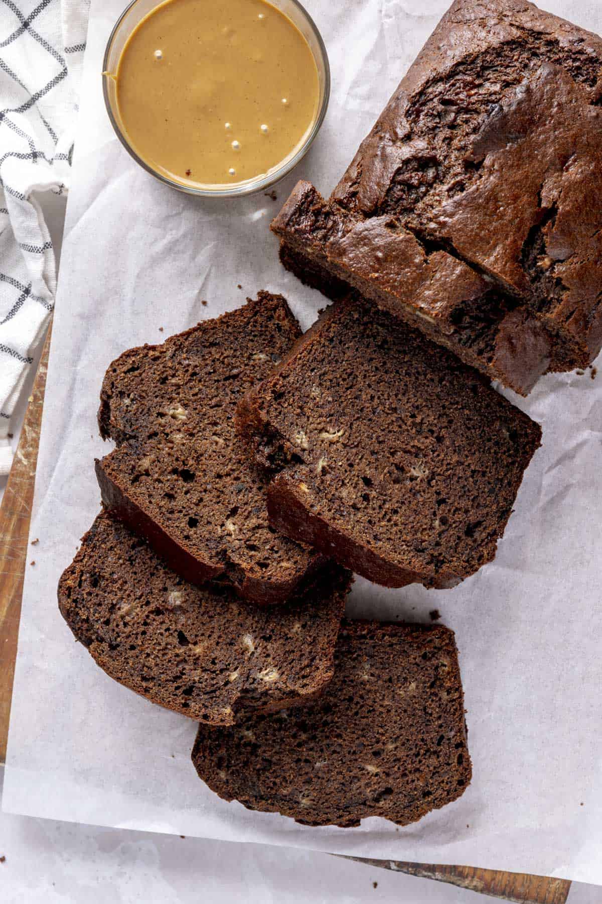 Loaf of chocolate peanut butter banana bread with a few thick slices cut and a small dish of peanut butter nearby.