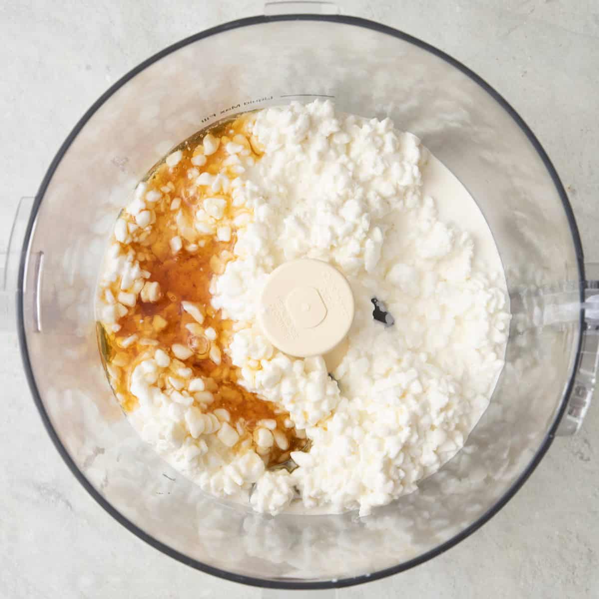 Cottage cheese and honey in a food processor before blending.