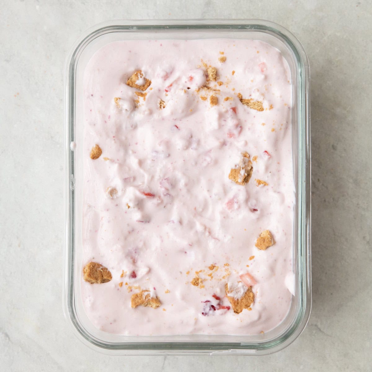 Strawberry cheesecake mixture added to a small glass dish before freezing.
