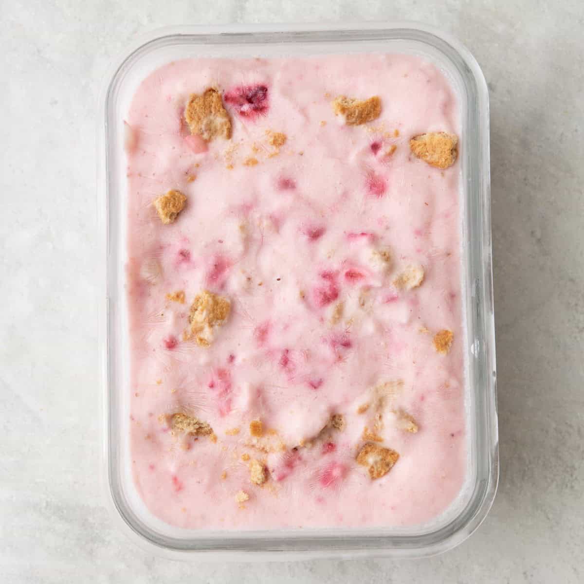 Strawberry cheesecake mixture added to a small glass dish after freezing.