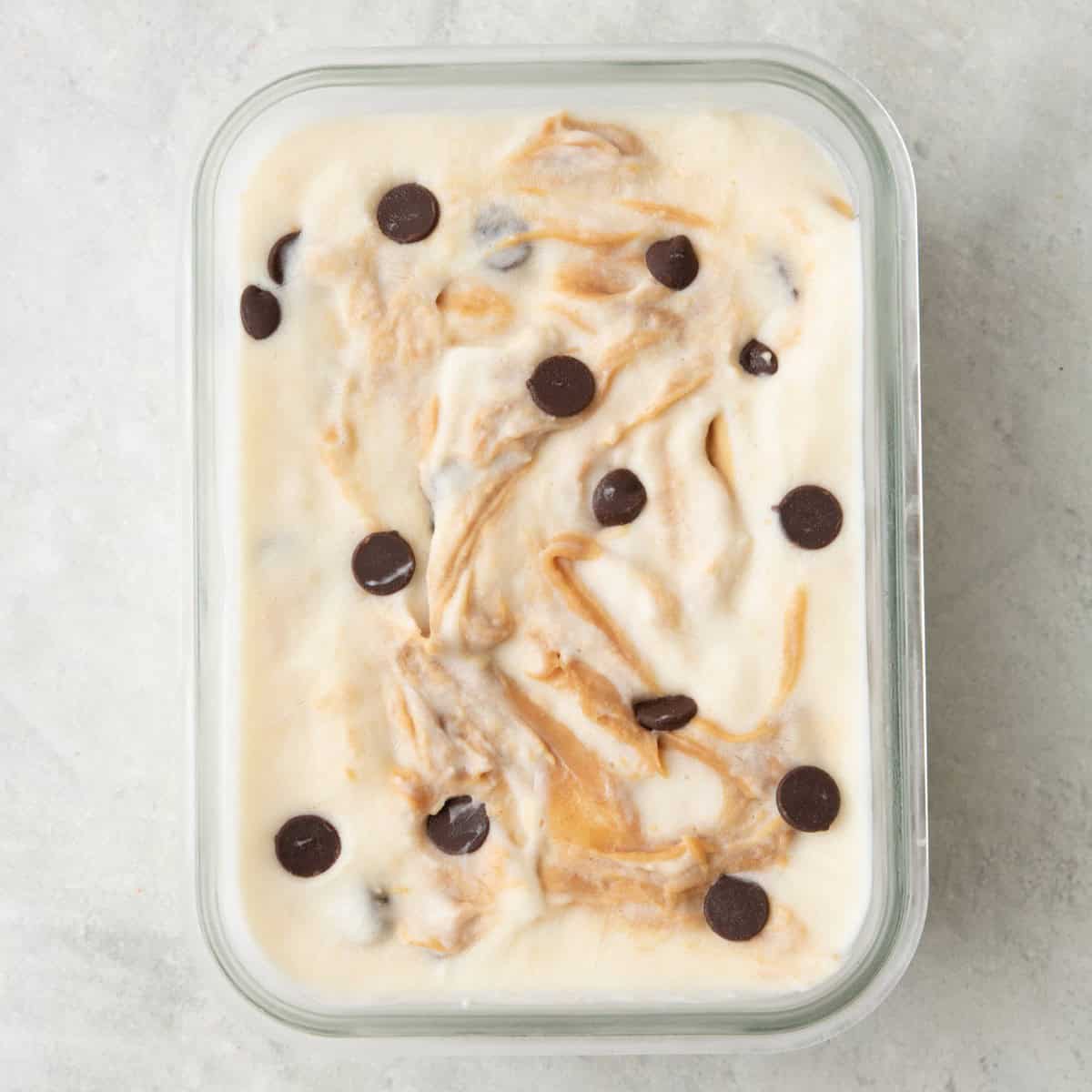 Peanut butter chocolate chip mixture added to a small glass dish after freezing.