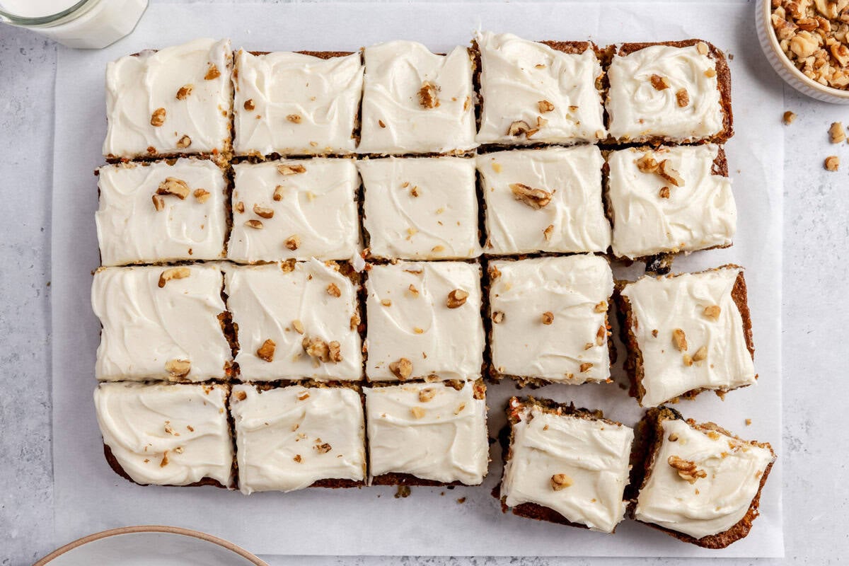 Easy carrot cake recipe cut into squares and topped with a homemade cream cheese frosting and walnuts.