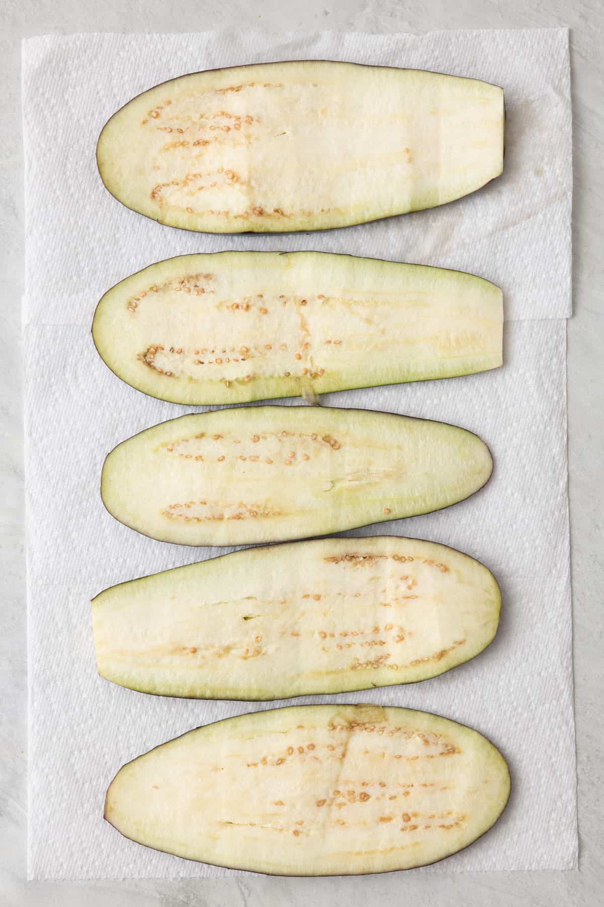 Eggplant slices/planks on paper towels sprinkled with salt.