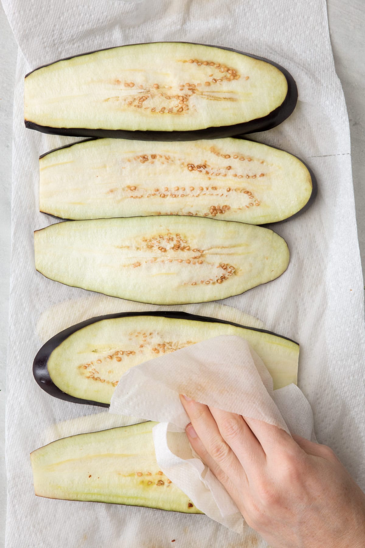Hand patting the slices dry with paper towels to remove extra moisture.