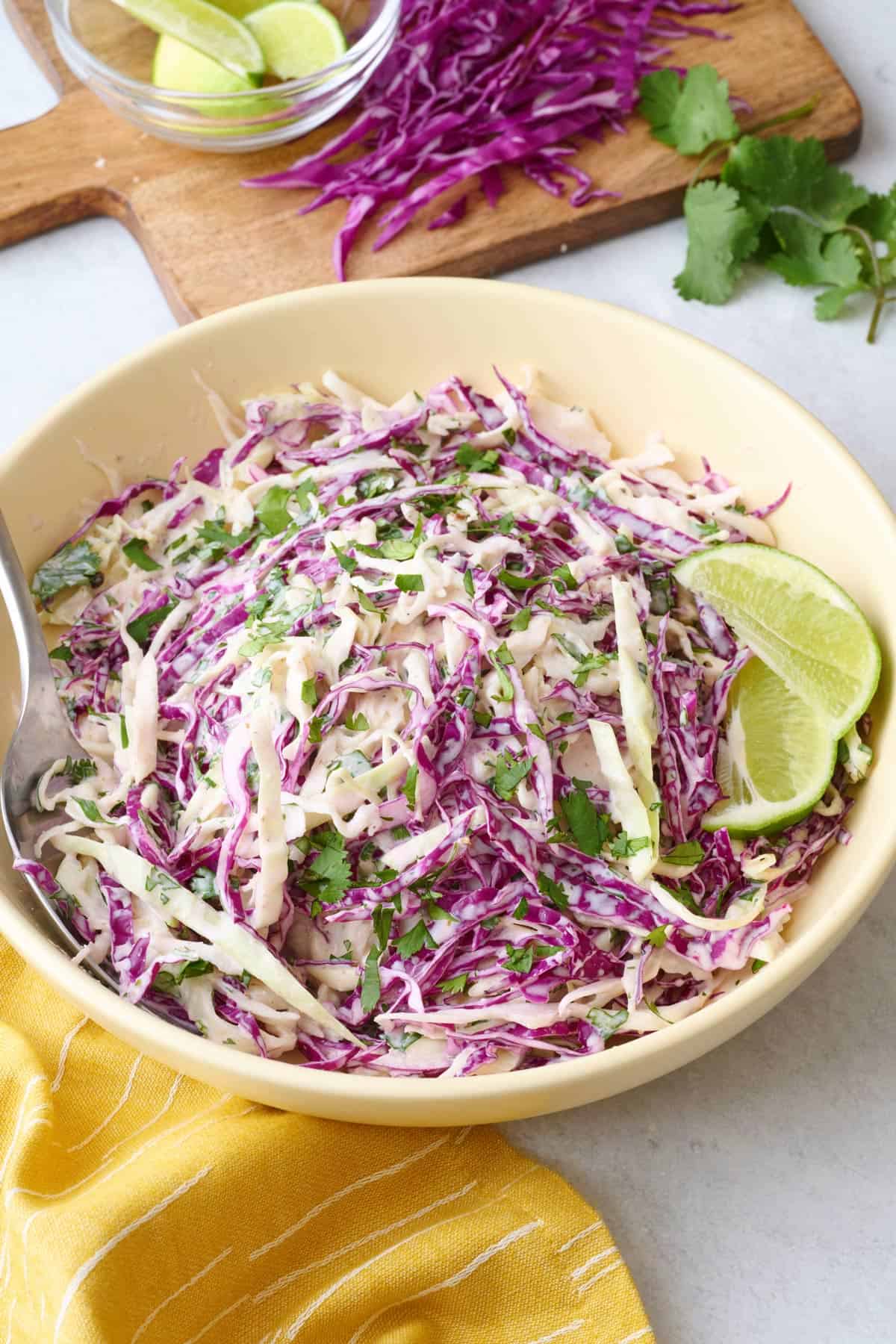 Quick fish taco cabbage slaw recipe in a bowl with lime wedges.