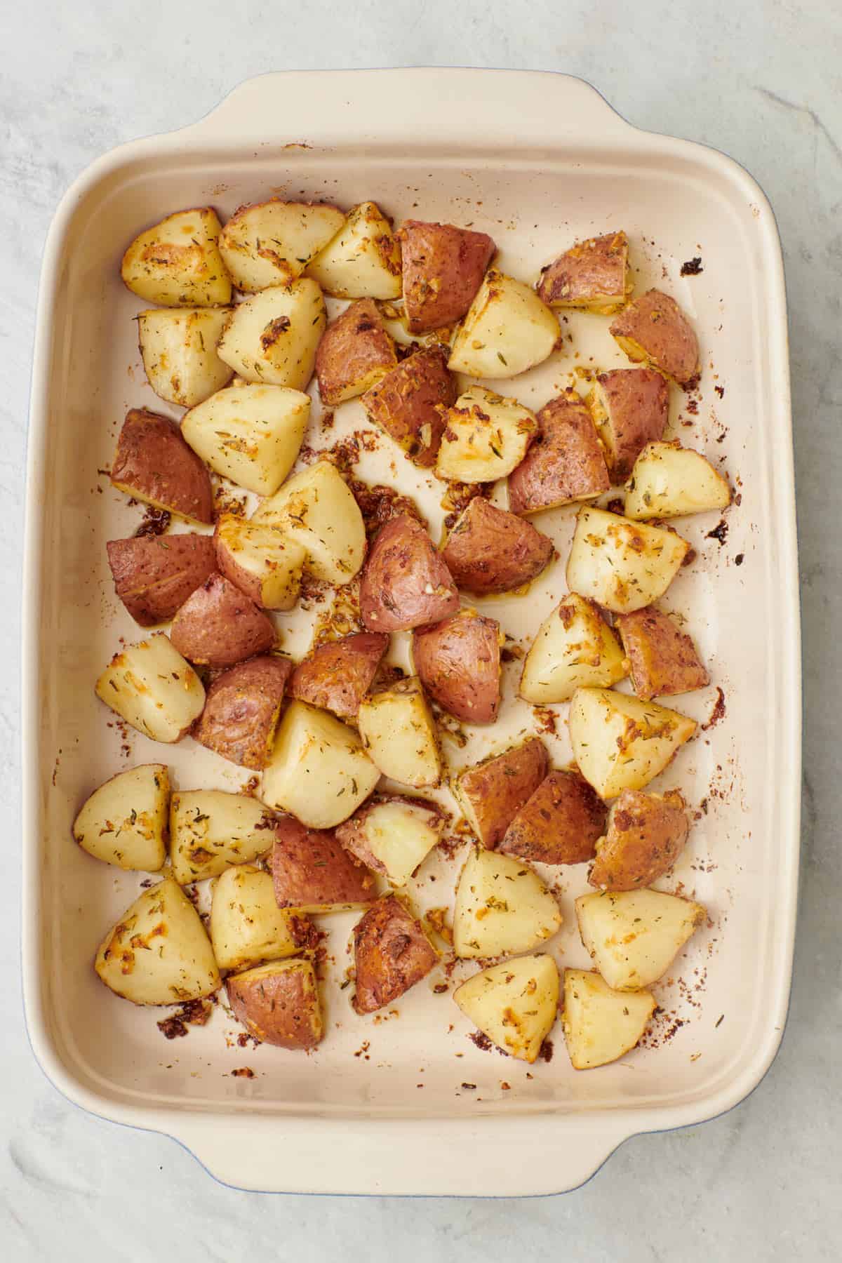 Seasoned potatoes in a baking dish after roasting.