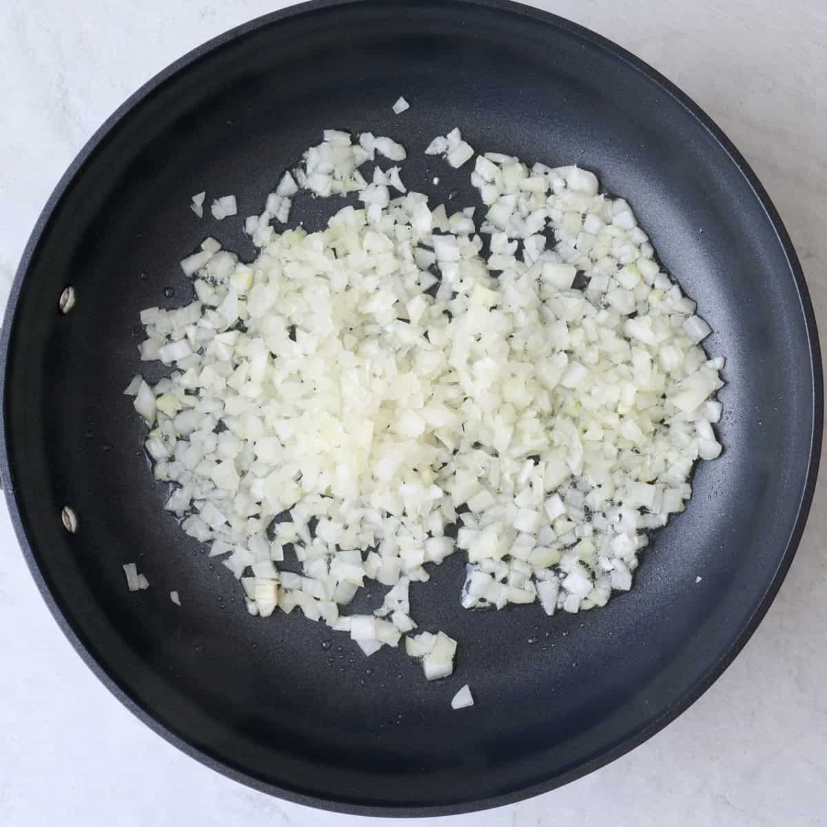 Diced onions in a skillet before cooking.