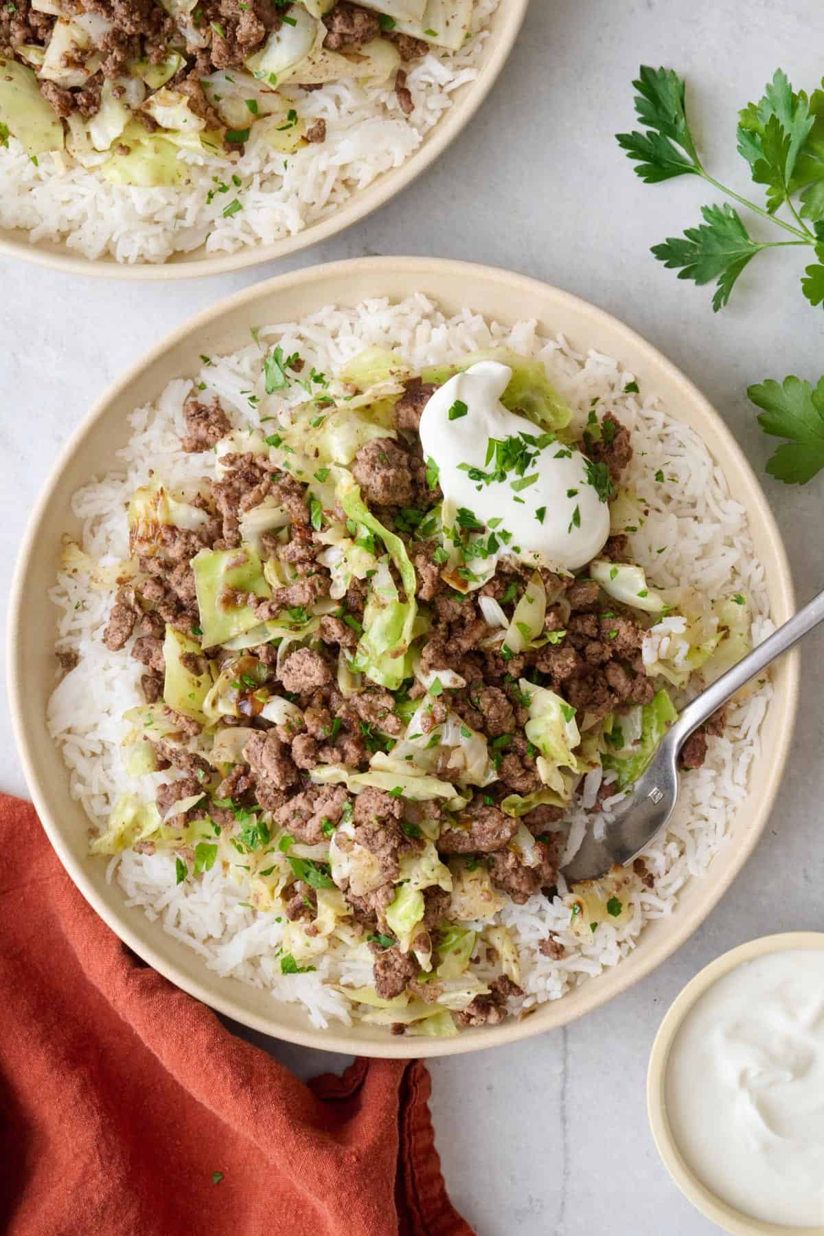 Lebanese spiced ground beef cabbage served over rice in a bowl with Greek yogurt on top.