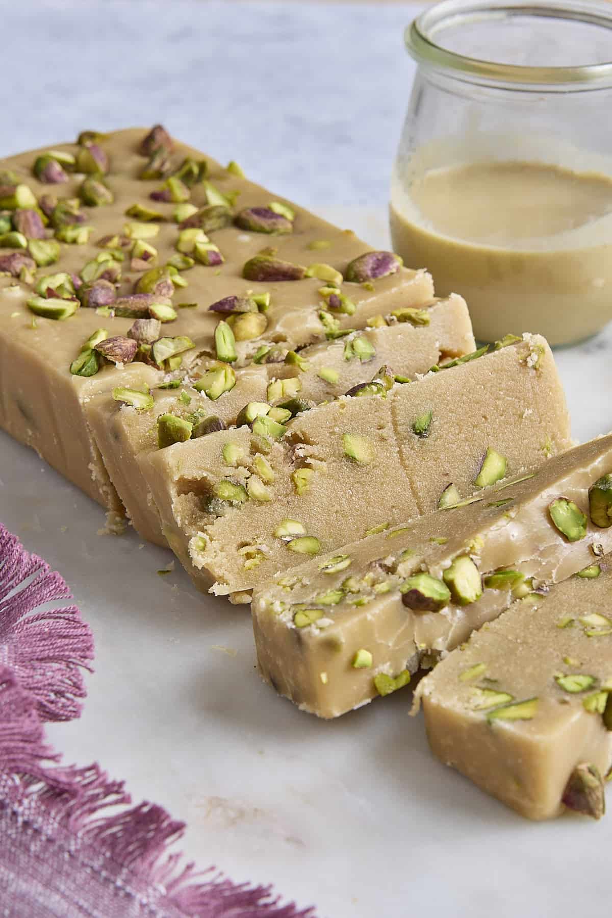Sliced homemade halva with pistachios with a few slice cut.