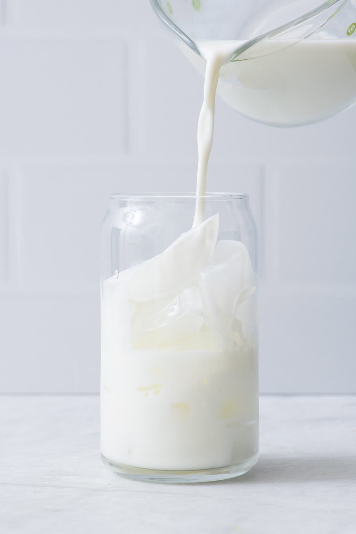 Pouring milking over a glass of ice.