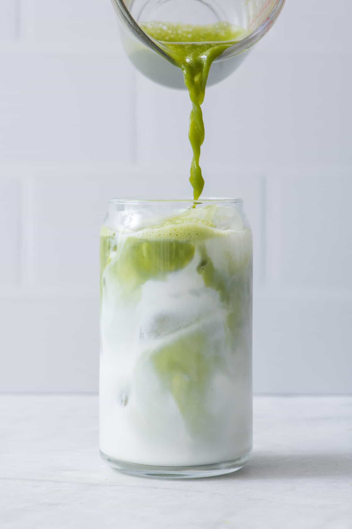Pouring matcha of iced milk in glass.