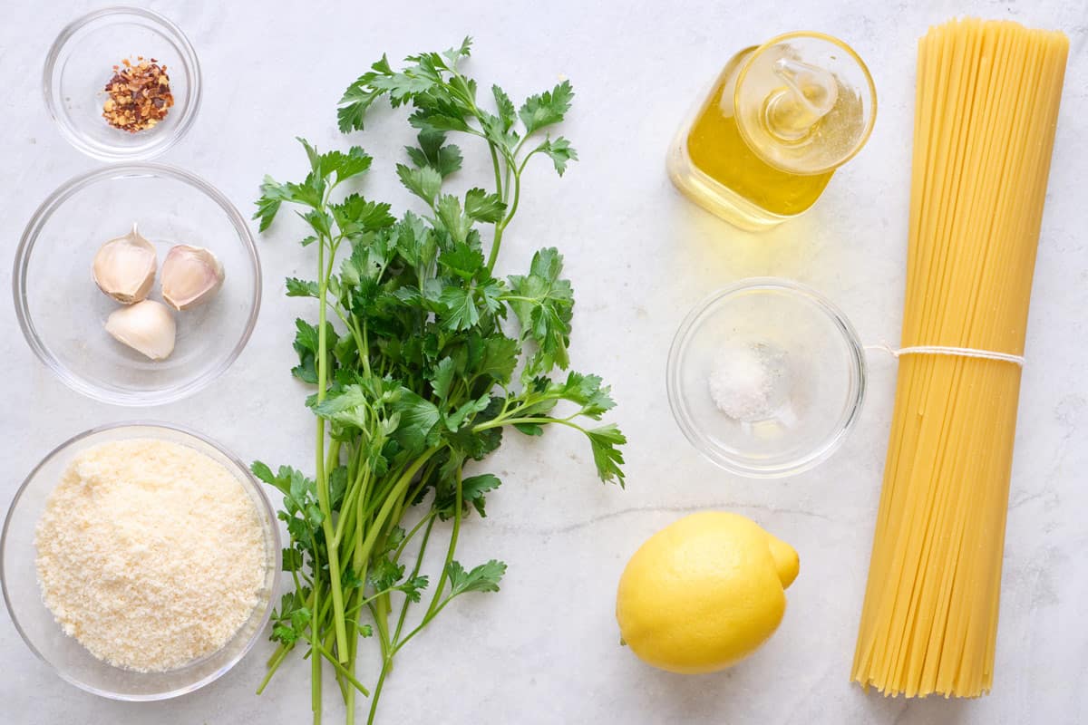 Ingredients for recipe: pepper flakes, garlic, grated parmesan, fresh parsley, oil, salt, lemon, and dry pasta.