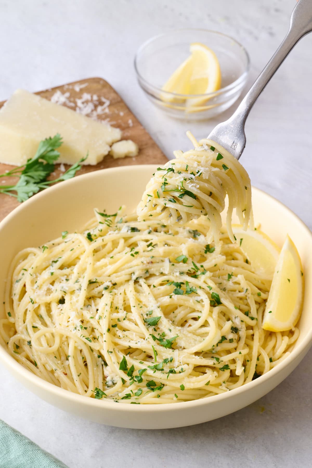 Lemon garlic pasta in a bowl with pasta twirled on a fork being lifted up.