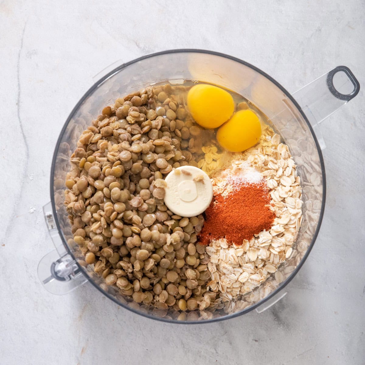 Mushroom mixture, lentils, eggs, oats, and seasoning in a food processor before processing.