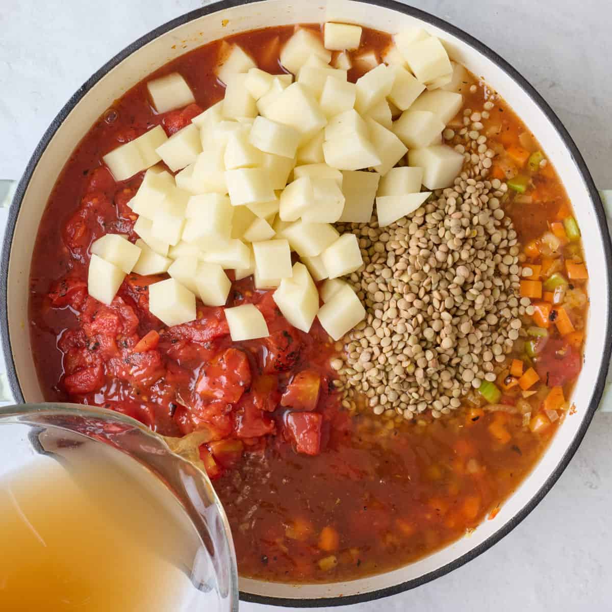 Salt, pepper, lentils, potatoes, tomatoes and broth added to pot.