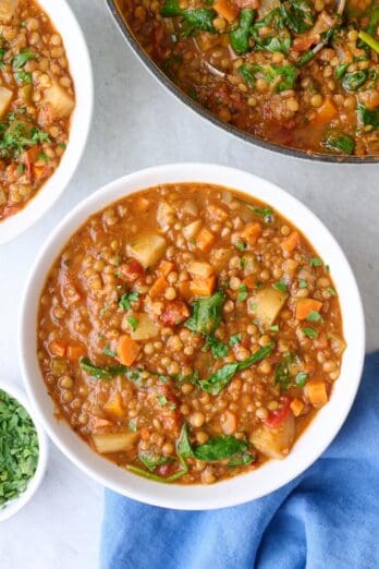 Two bowls of lentil stew with pot nearby.