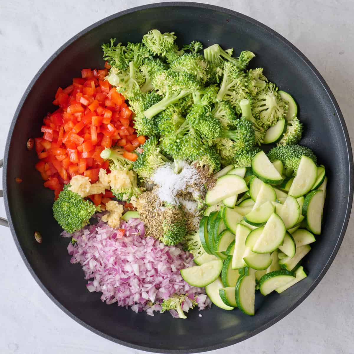 Chopped broccoli, onions, red pepper, zucchini and garlic in a skillet with Italian seasoning, salt and pepper.
