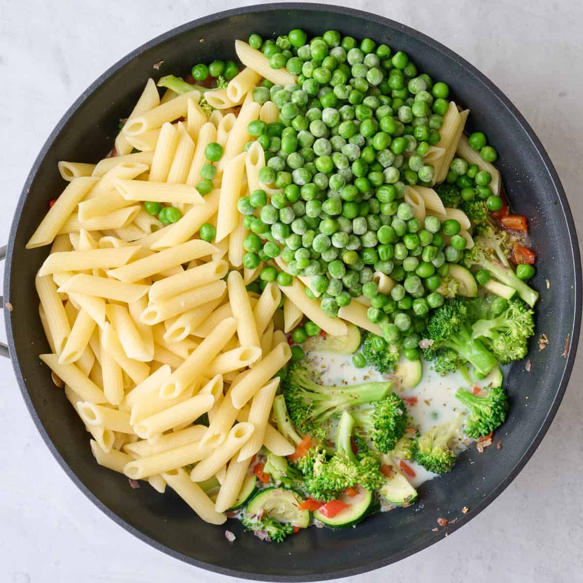 Cooked pasta, peas, milk, and reserved pasta water added.