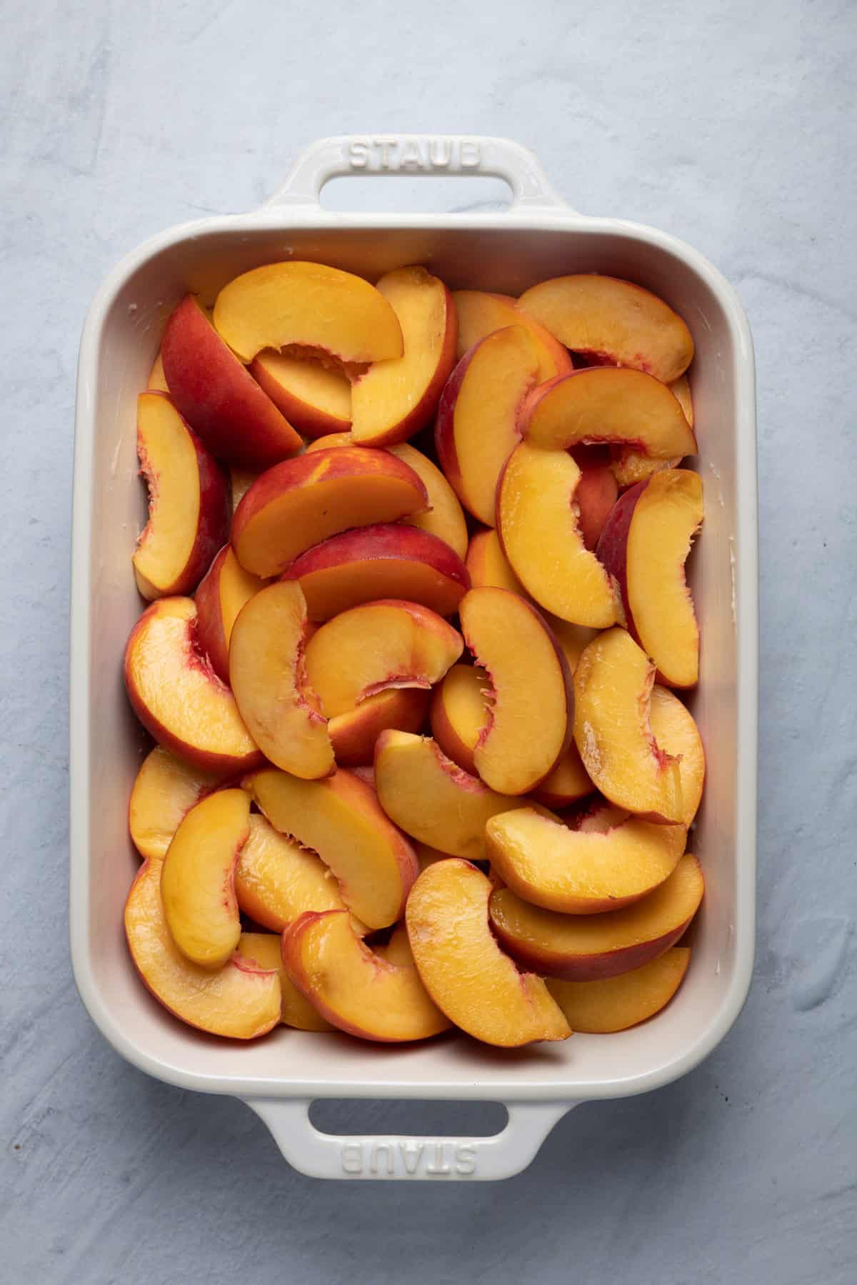 Sliced peaches in a baking dish.