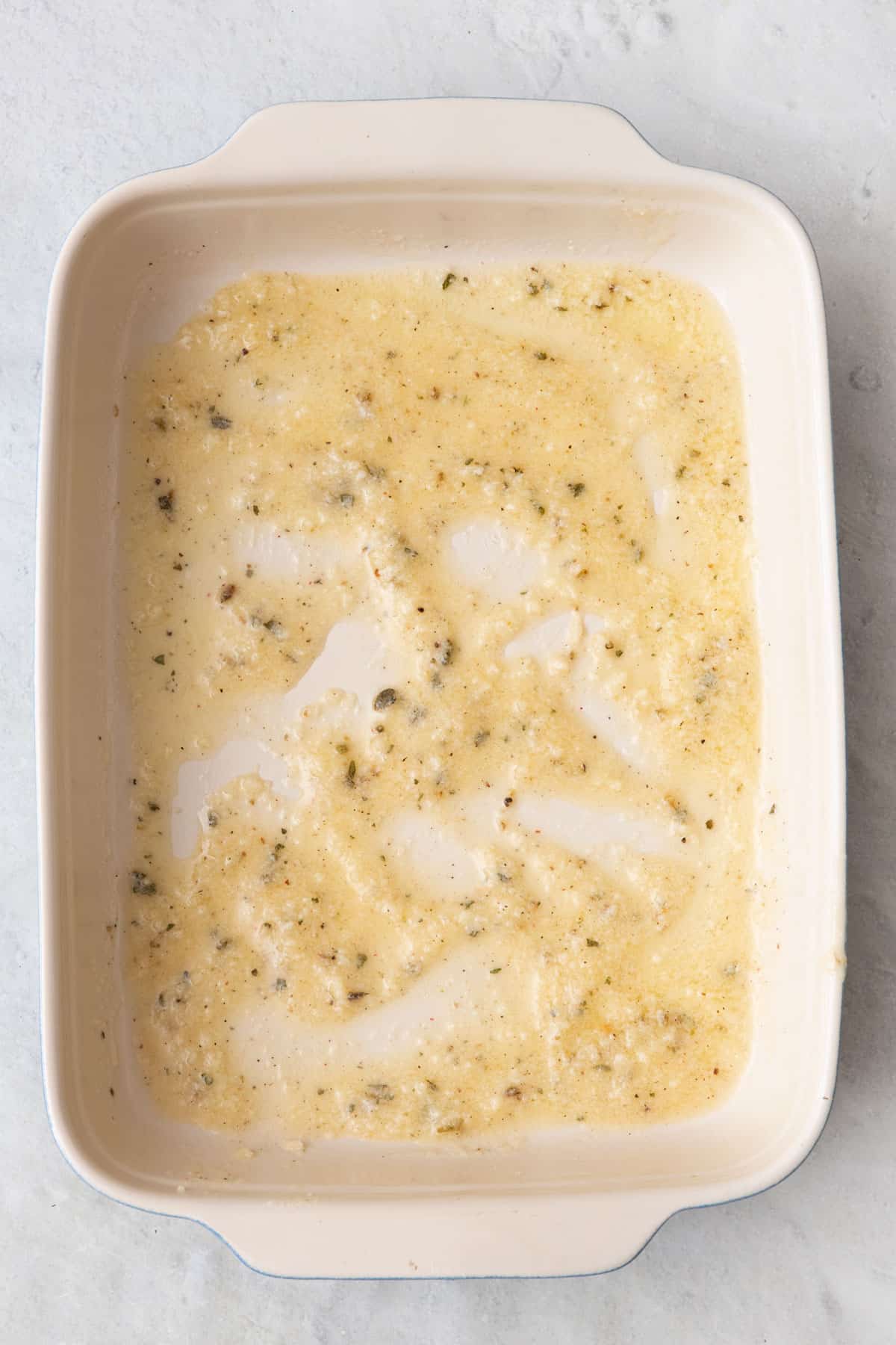 Melted butter, seasonings, and cheese in a baking dish.