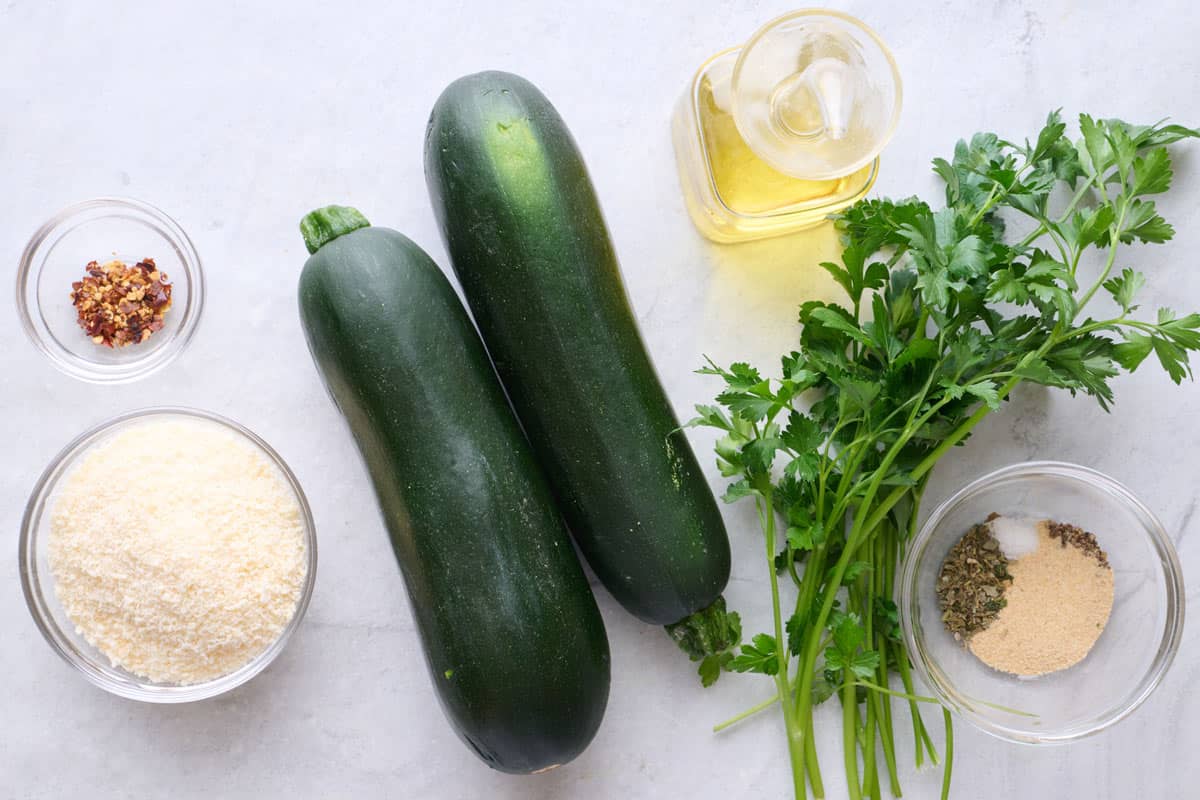 Ingredients for recipe: red pepper flakes, grated parmesan, zucchini, oil, parsley, and seasonings.