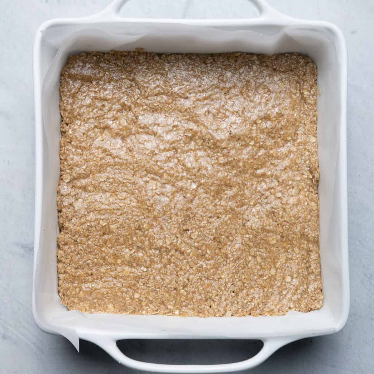 Oat bar mixture pressed into a baking dish.