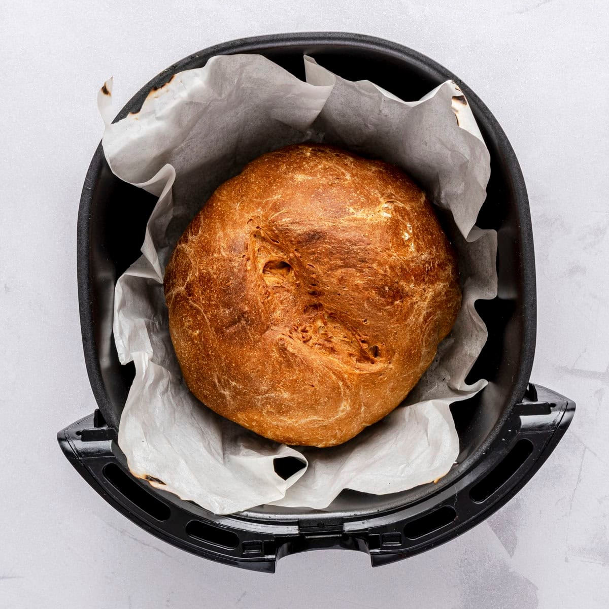 Bread after finished cooking, flipping top side to show well browned crust.