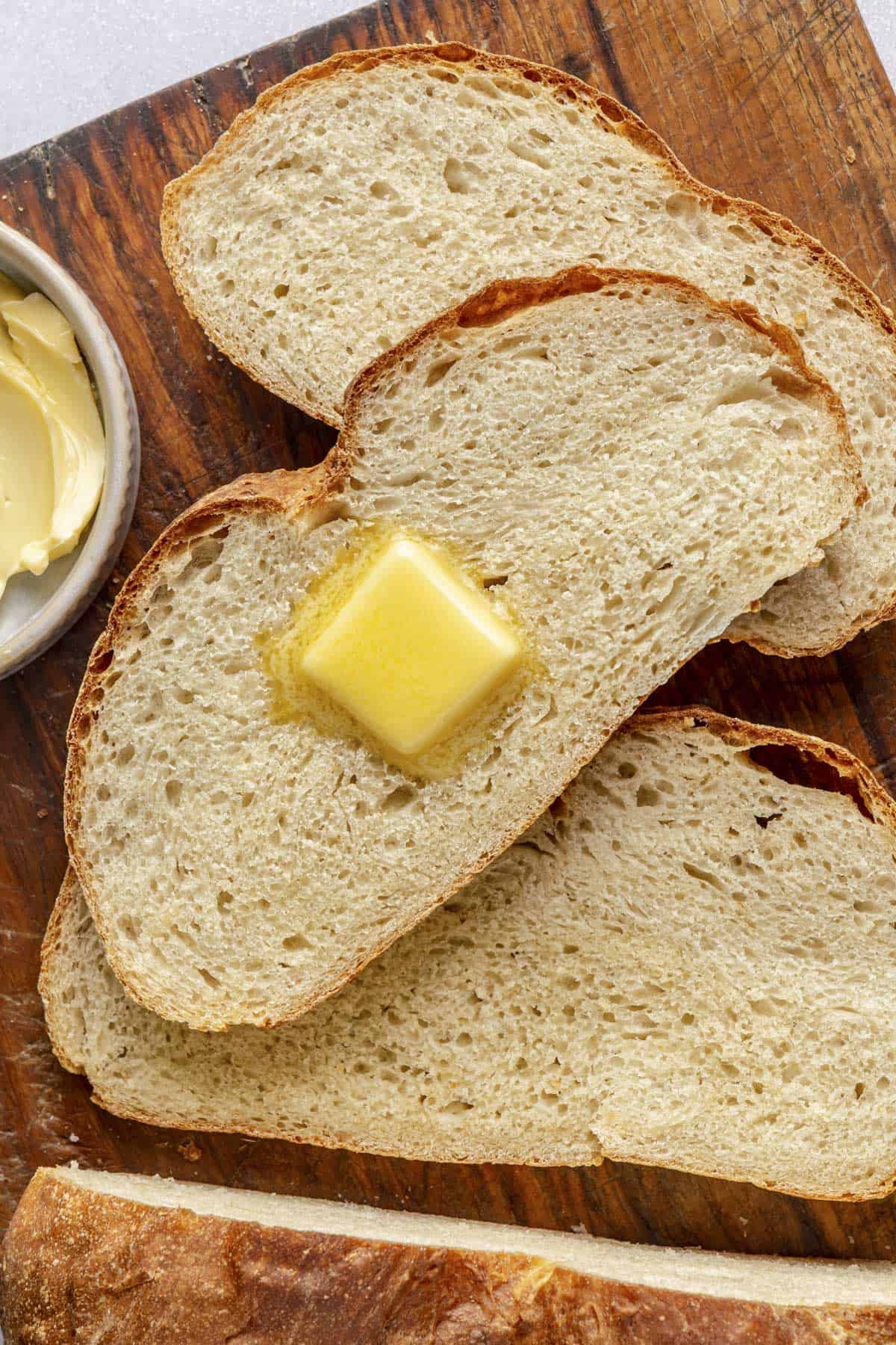 A few slices o air fryer bread with a pat of butter on one.