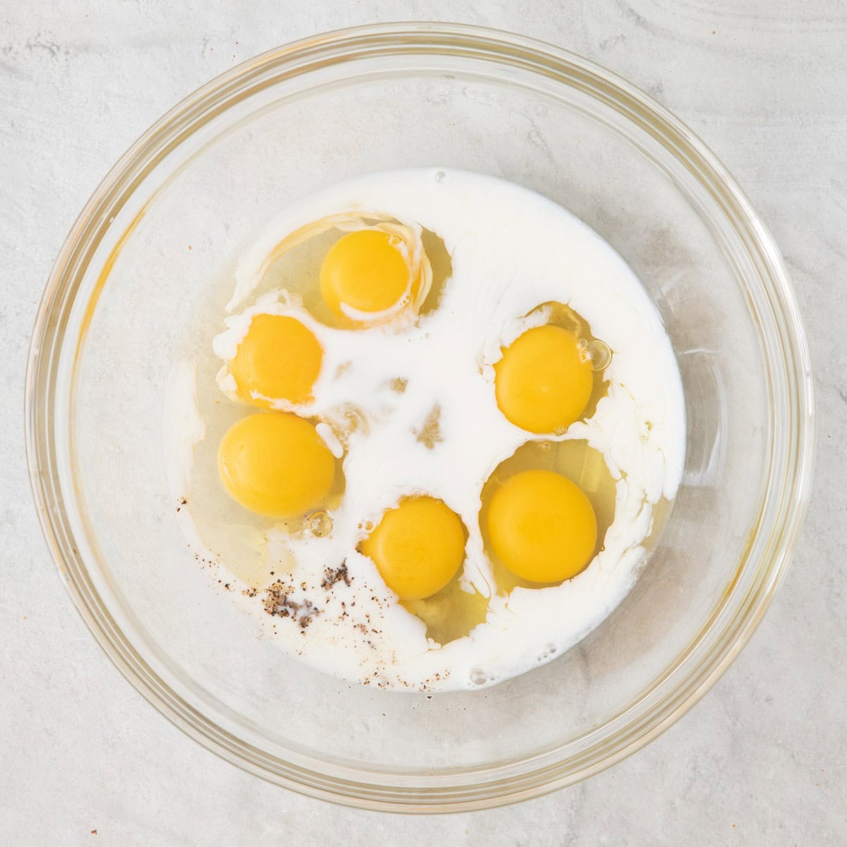 Eggs, milk and seasoning in a bowl before whisking.