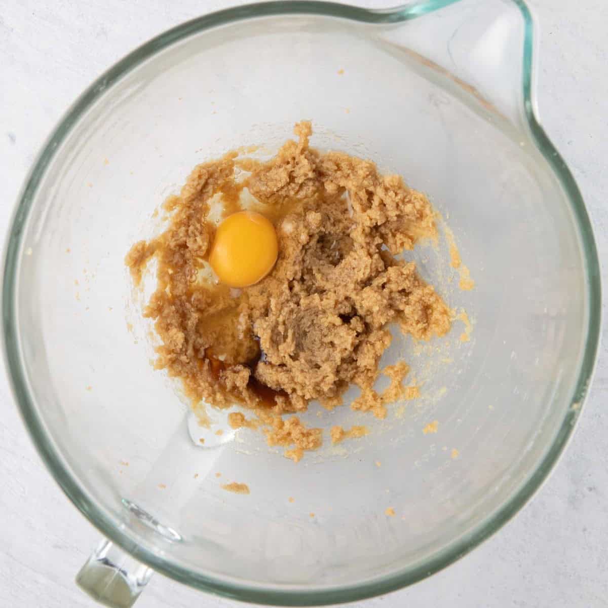 Butter mixture and applesauce combined with an egg added, before mixed in.