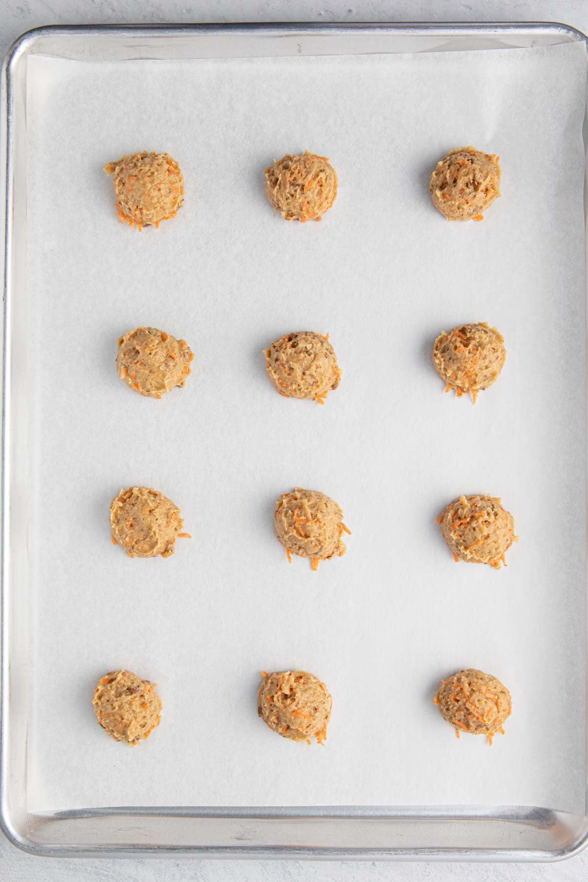 Cookie dough on a baking sheet spaced before baking.