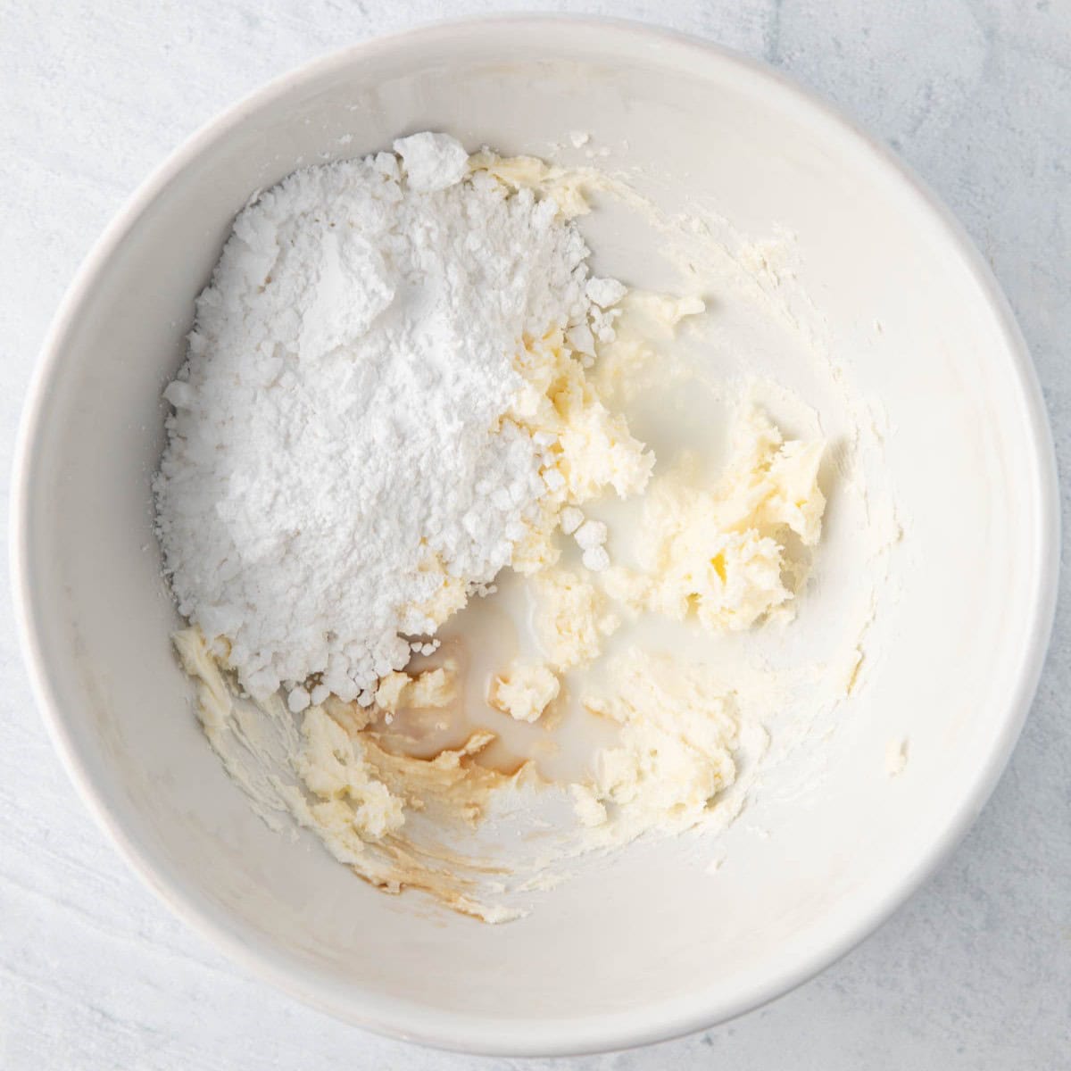 Cream cheese and butter after creamed together with powdered sugar, vanilla, and milk added.