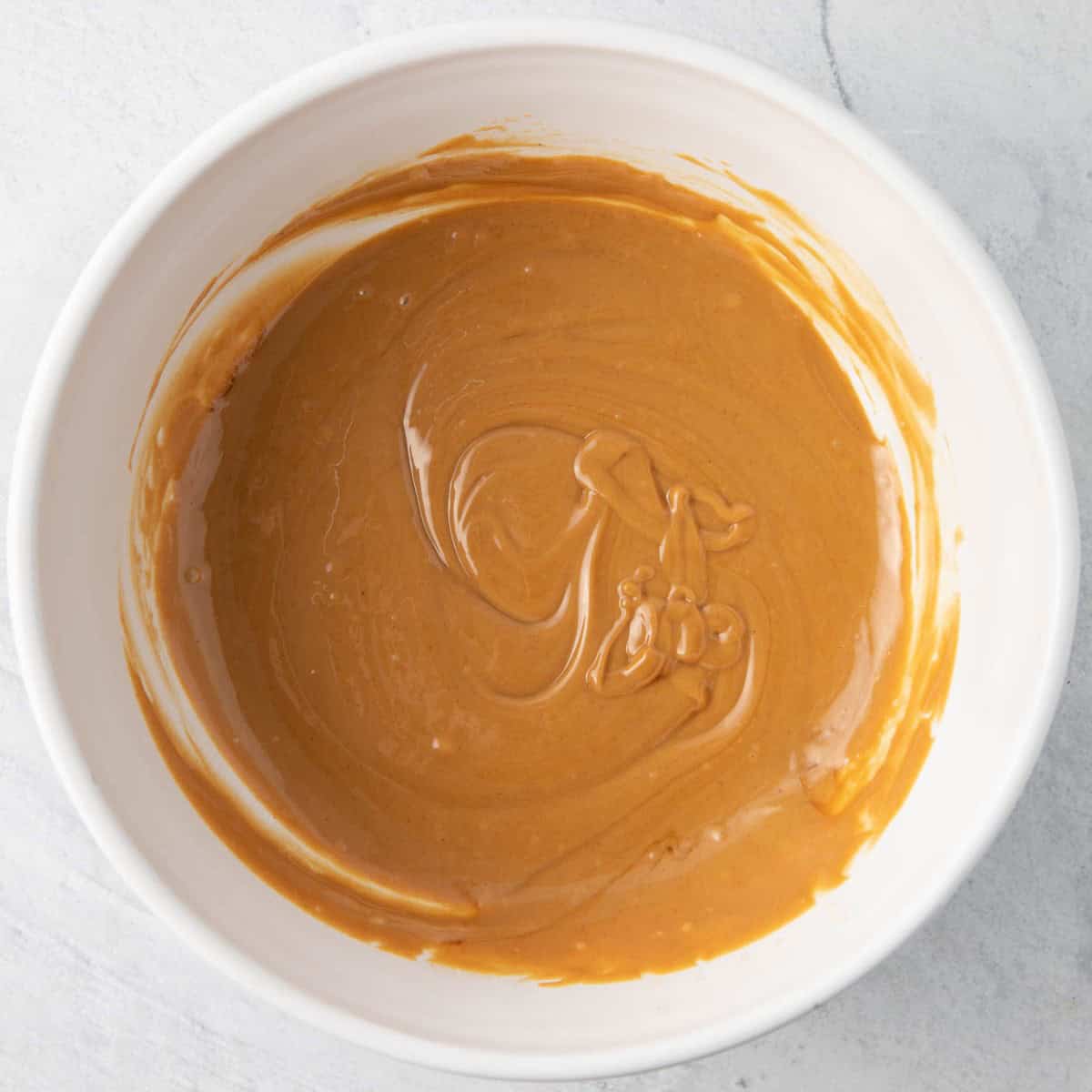 Peanut butter and butter in a bowl melted and combined with vanilla.