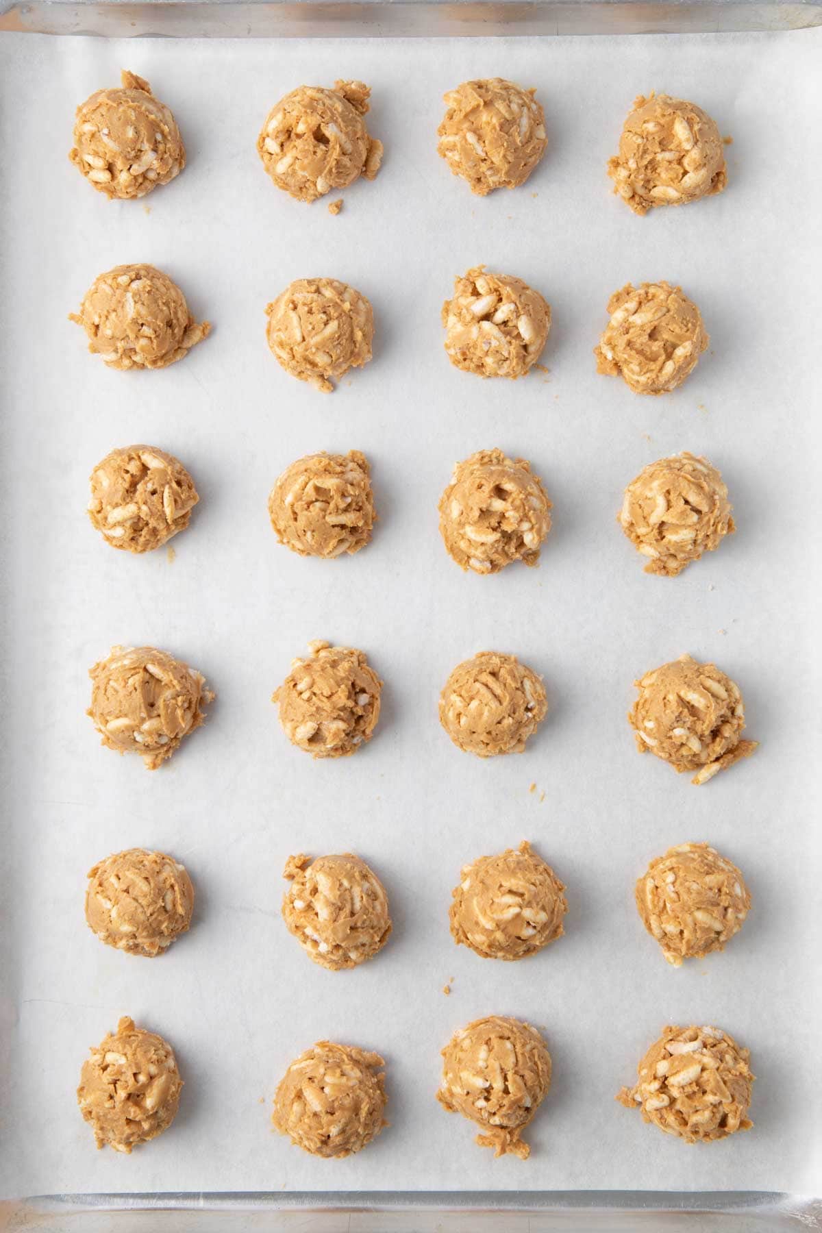 Cookie scoop sized balls of mixture on a parchment paper lined baking sheet.