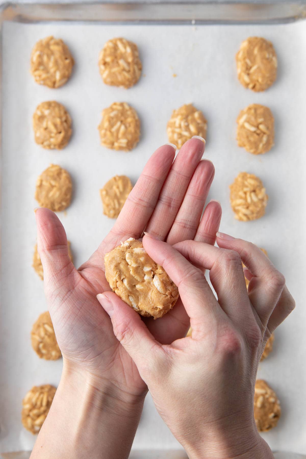 Hands shaping peanut butter mixture into egg shapes.