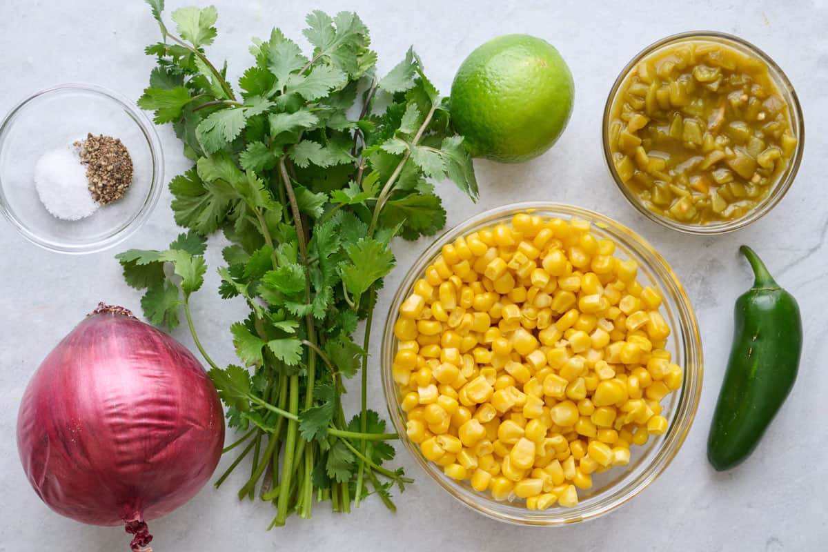 Ingredients for recipe: salt and pepper, red onion, cilantro, lemon, thawed frozen corn, green chilis and jalapeno.