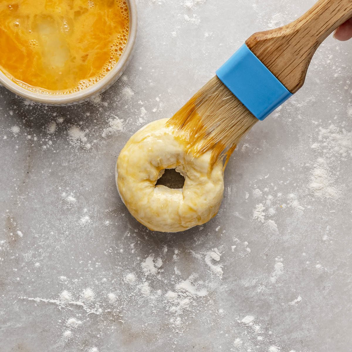 Brushing one bagel with egg wash.