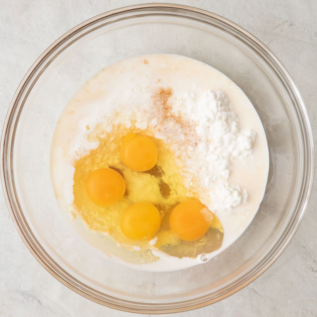 Eggs, cottage cheese, milk, maple syrup, and vanilla in a bowl before whisking.