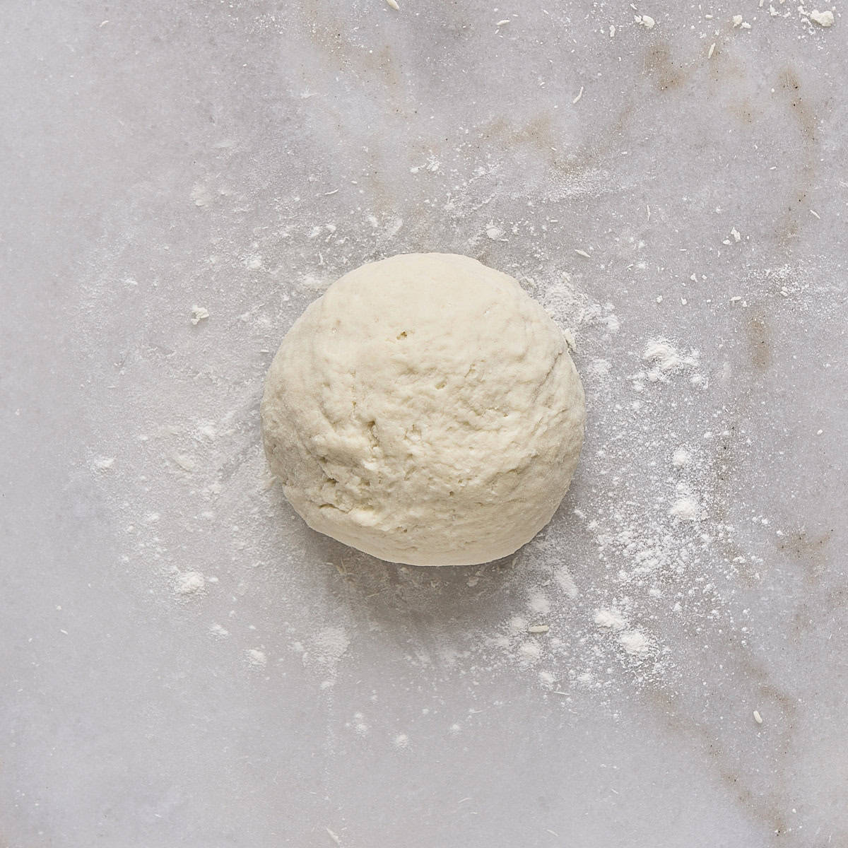 Dough on a lightly floured surface after kneading into a smooth ball.