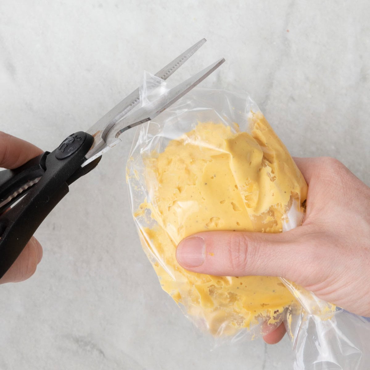 Egg filling in a zip top bag with scissors cutting of the tip.
