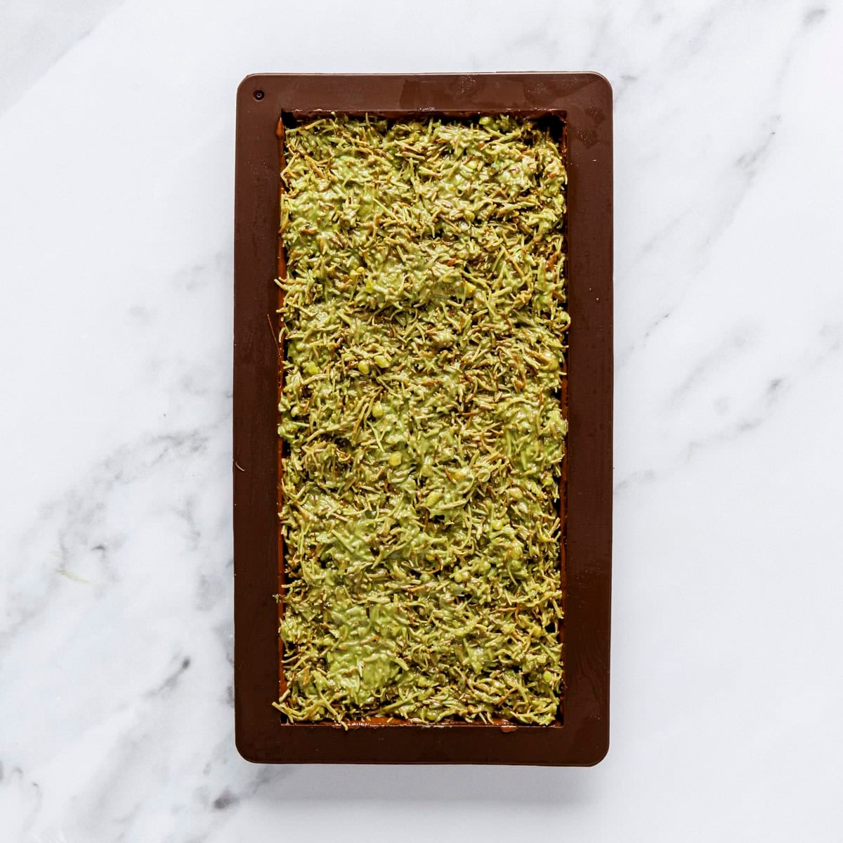 Pistachio filling added to chocolate bar mold.