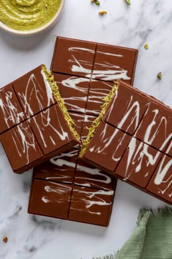 Two Dubai chocolate bars with one split in half to show green pistachio filling.